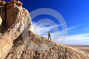 Unrecognisable man climbing a coloured hill with exploding like cloud movement in Tsagaan Suvraga Â«Â white stupaÂ Â» in the Gobi